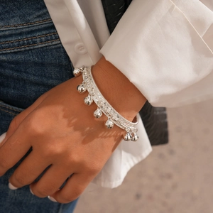 Gros plan d'un bracelet à breloques clochettes en argent porté sur un poignet de mannequin