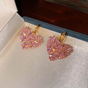 Macro d'oreilles en cœur avec zircon rose sur soie blanche dans une boîte à bijoux