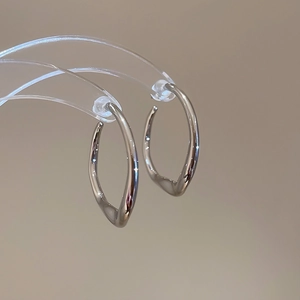 Detail view of irregular twisted silver earrings with a high-polished liquid metal finish
