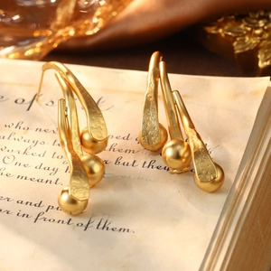Detailed macro of vintage style gold drop earrings with intricate floral relief textures