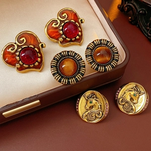 Detailed macro shot of vintage resin heart earrings and golden unicorn embossed studs