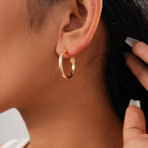 Close-up of elegant gold geometric hoop earrings worn by a model for a stylish look