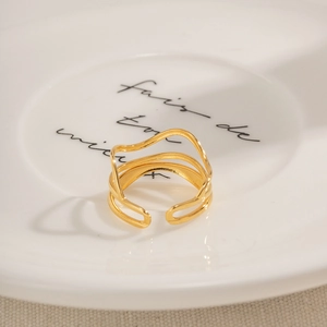Makro-Detail von goldenem Wellenring auf weißem Porzellanteller mit Handschrift