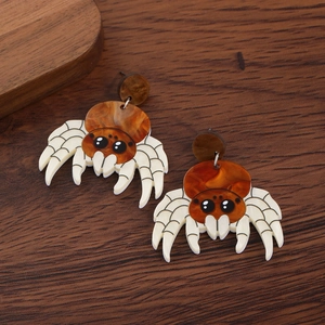 Detail of brown spider acrylic earrings with grid pattern legs on wood background