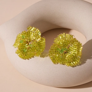 Orecchini a fiore in perle di vetro verde su espositore in pietra bianca minimal