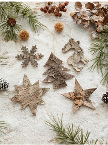 Detail of five rustic wooden Christmas ornaments on snow with pine cones and red berries