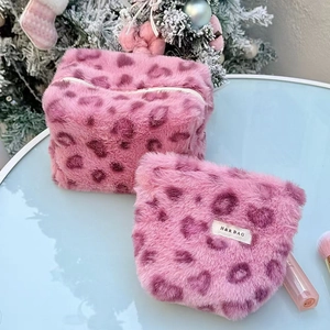 Close-up of pink leopard print plush makeup bags on a festive table setting