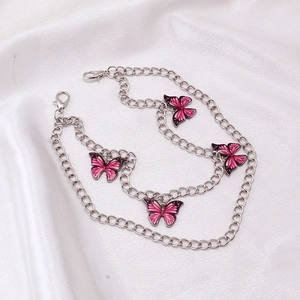 Details der rosa Schmetterlingsanhänger an einer silbernen Kette auf weißem Satin
