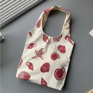 Minimalist beige canvas tote bag with red marine life prints and sturdy handles