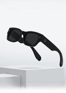 Detail of black rectangular thick frame sunglasses with golden star-shaped rivets