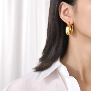 Polished gold hollow geometric hoop earrings on model featuring minimalist huggie style