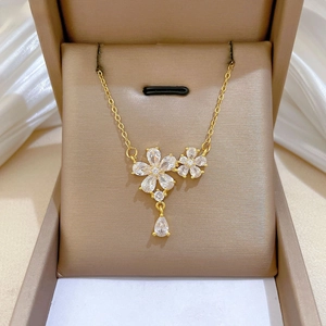 Close-up of gold five-leaf flower pendant with sparkling zircons and a teardrop crystal