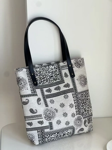 Detailed view of paisley canvas tote bag with black leather straps and metal rivets