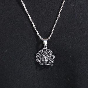 Close-up of vintage silver Medusa pendant with relief details on black fabric background