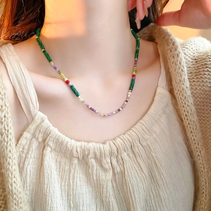 Close-up of handmade colorful beaded necklace with green malachite and purple beads