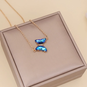 Minimalist gold necklace with blue crystal butterfly pendant on jewelry display box