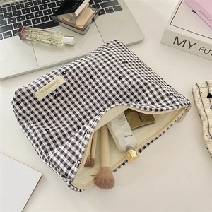 Detail of checkered makeup bag showing spacious interior with brushes and skincare