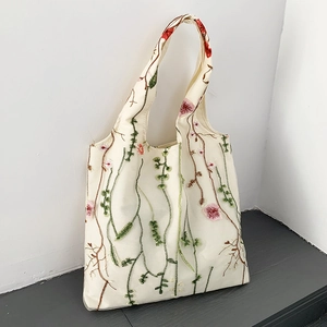Close-up of floral embroidery detail on cream canvas tote bag for beach or shopping