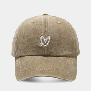 Detail of vintage washed khaki baseball cap with white double heart embroidery decoration