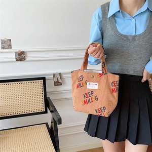 Detail of corduroy tote bag with Keep Smiling print and vintage orange texture