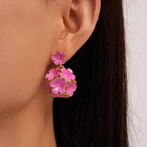 Détail des boucles d'oreilles fleurs en émail rose fuchsia avec bordure dorée