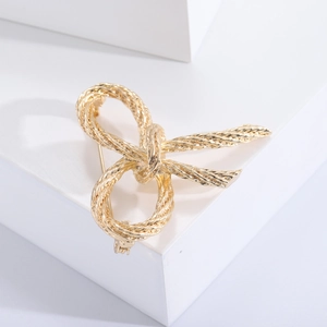 Close-up of golden bow knot brooch with intricate braided nautical rope texture