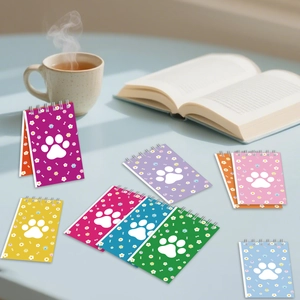 Detailed view of colorful dog paw spiral notebooks on a blue desk with a cozy tea setup