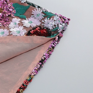 Détail des paillettes florales et broderies de luxe sur le tissu en maille rose