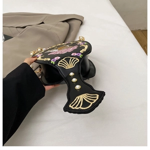 Detailed close-up of fan-shaped handle with floral embroidery and pearl rivets on the bag