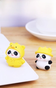Close-up of cute panda figurines in yellow raincoats on a wooden desk setup