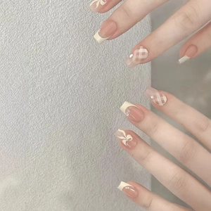 French tip press-on nails with pink base, brown plaid patterns, bows and pearls