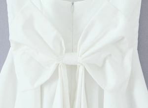Close-up of a large white bow decoration and invisible zipper on the back of a mini dress