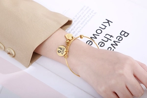Nahaufnahme des goldenen Armbands mit Herz-Anhänger und LOVE-Gravur am Handgelenk