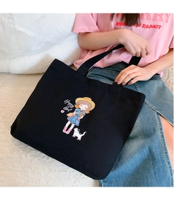 Detail of black canvas tote bag featuring a cute cartoon girl and cat graphic print