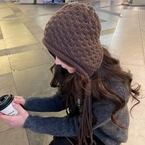 Detailed texture of thick knit winter hat with ear flaps and long tassel ornaments