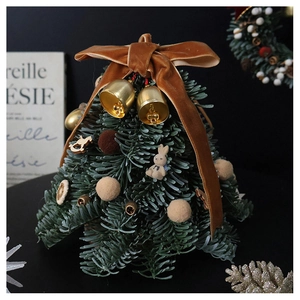 Detailed view of mini Christmas tree with velvet bow, bells, and handmade ornaments