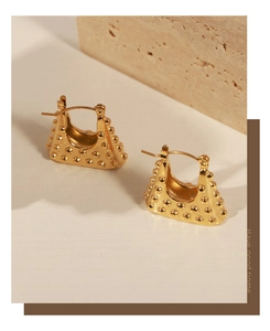 Detailed view of golden trapezoid earrings with vintage polka dot texture and cut-out design