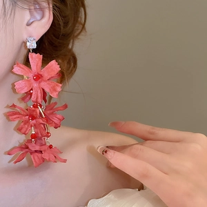 Close-up of red fabric flower drop earrings with crystal studs and bead tassels on model