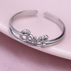 Macro shot of silver stainless steel ring with Love lettering on pink fabric