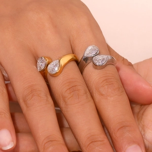 Close-up of dual teardrop zircon open rings in gold and silver finish on hand