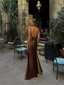 Detail view of a brown satin maxi dress showing the low back cut and delicate spaghetti straps