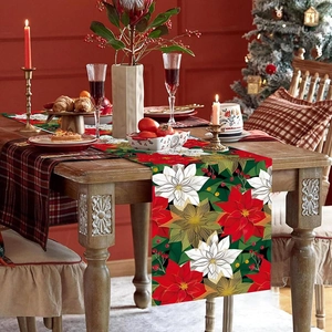 Festive Christmas table runner with red poinsettia floral patterns on a wooden dining table