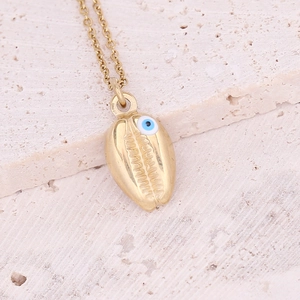 Macro view of golden shell pendant with blue evil eye on stainless steel chain