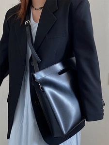 Fashionable black leather tote bag featuring adjustable shoulder straps and handle detail