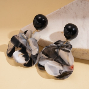 Close-up of ink-wash resin flower earrings on marble stand with elegant light tones