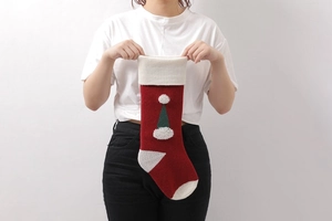 Close-up of a red knitted Christmas stocking with plush trim and Santa hat applique