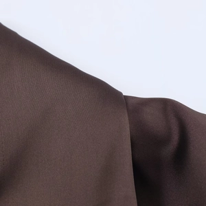 Close-up of brown satin fabric texture showing smooth glossy finish on the dress