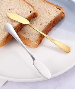 Détail de couteaux à beurre en acier inoxydable doré et argenté sur une assiette