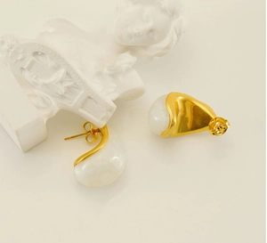 Détail des boucles d'oreilles dorées 18k avec résine blanche et design fluide