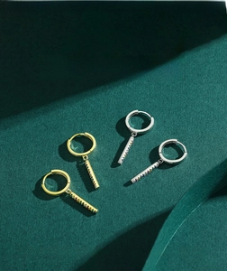 Macro detail of gold and silver hoop earrings with vertical rainbow pavé zircon bar charms